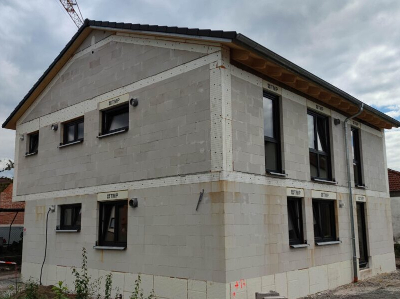 Neubau eines zweistöckigen Einfamilienhauses mit Fensterrahmen und moderner Dämmung.